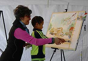 A young visitor gets some hands on experience with watercolor painting