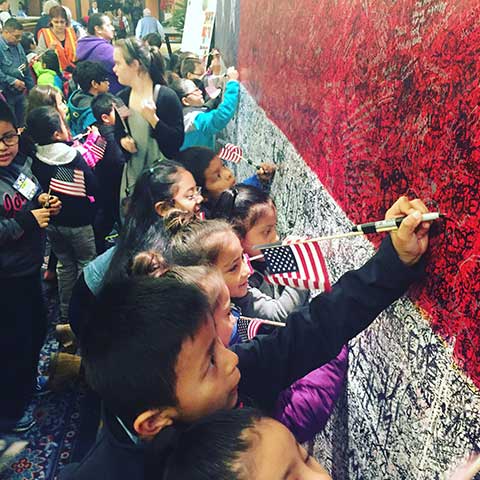 Children writing hero messages on Hometown Hero arriving at ArtPrize Seven