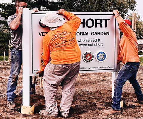 Workers installing Cut Short Veterans Memorial Garden sign during construction
