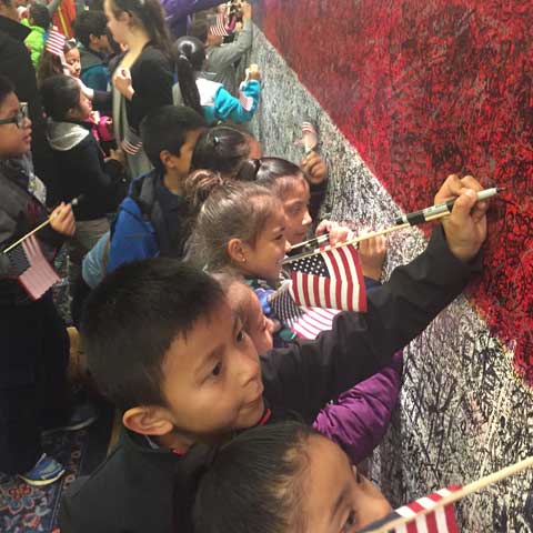 Children at ArtPrize Ten writing hero messages on Hometown Hero installation