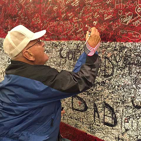 Elderly man writing hero message on Hometown Hero installation at ArtPrize Ten