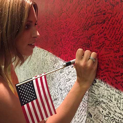 Young woman writing hero message on Hometown Hero installation at ArtPrize Ten