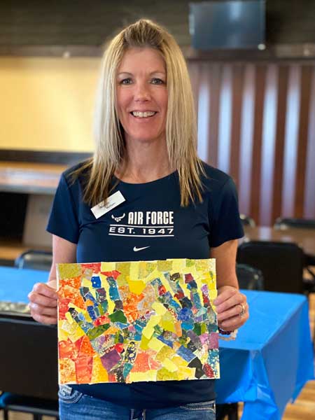 A veteran workshop participant shows off her painting for Yellow Ribbon installation